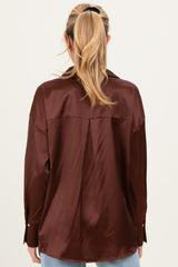 woman wearing a brown satin maternity shirt, showing the back view with a relaxed fit and buttoned cuffs
