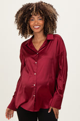 woman wearing a burgundy satin maternity shirt with buttons and a relaxed fit, showcasing her baby bump