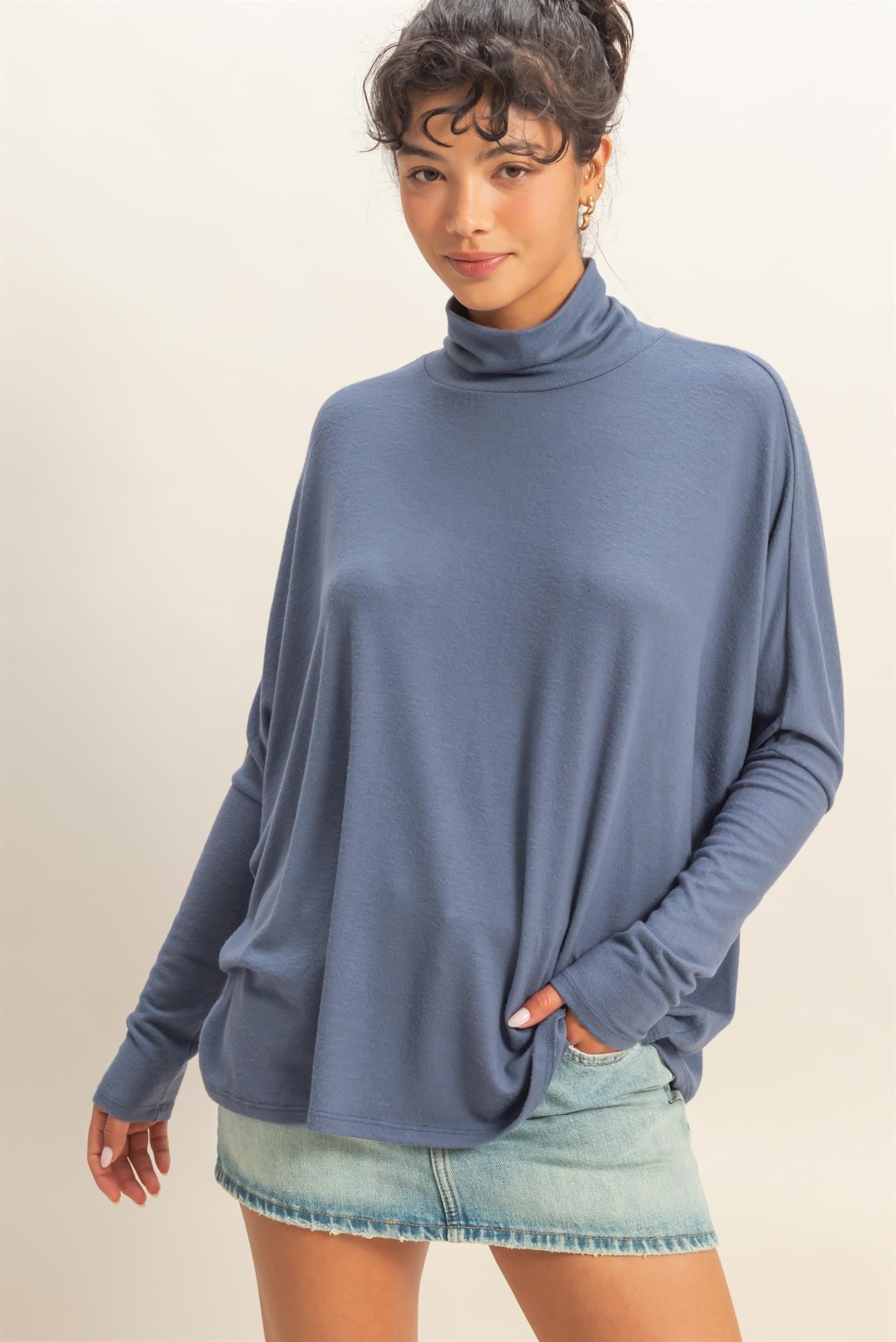 woman wearing a relaxed fit blue turtleneck top paired with a denim mini skirt