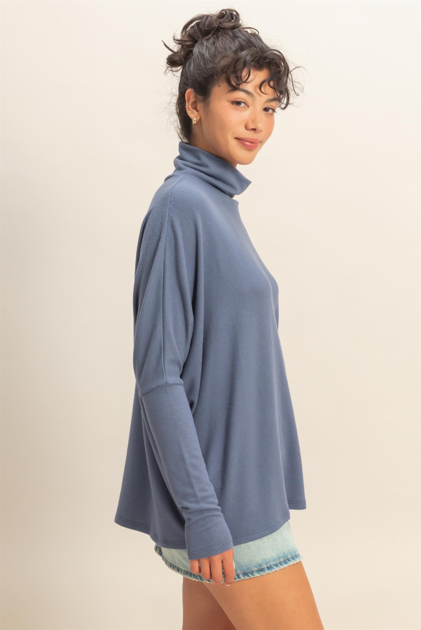 woman wearing a light blue long sleeve turtleneck top paired with denim shorts