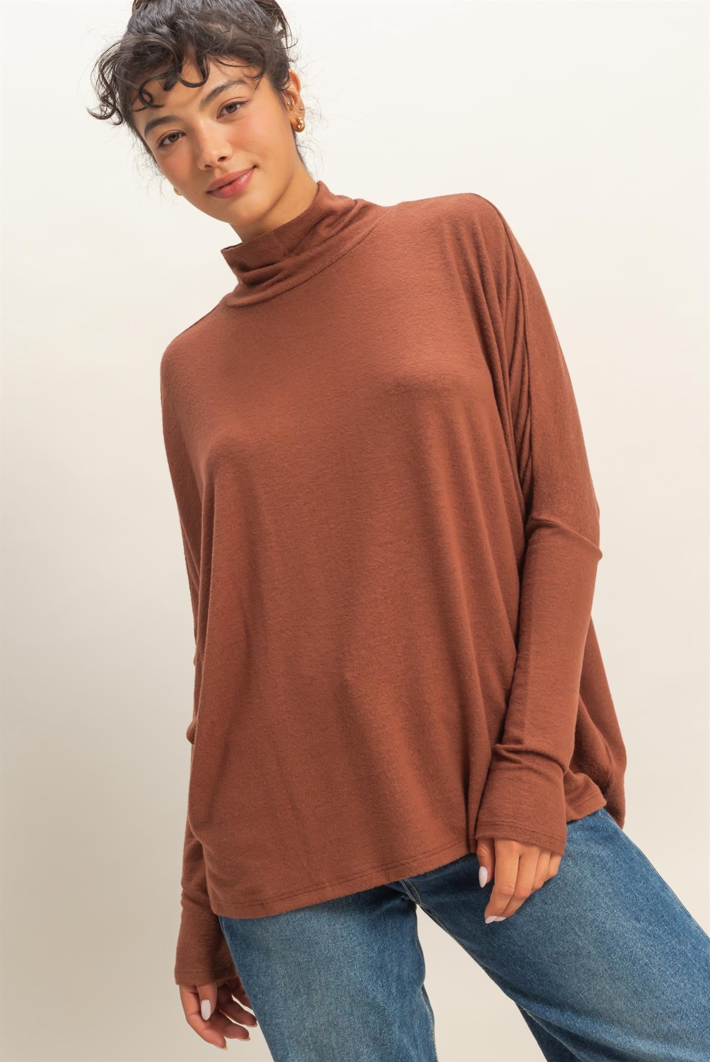 woman wearing a rust-colored turtleneck long sleeve top with relaxed fit and dropped shoulders