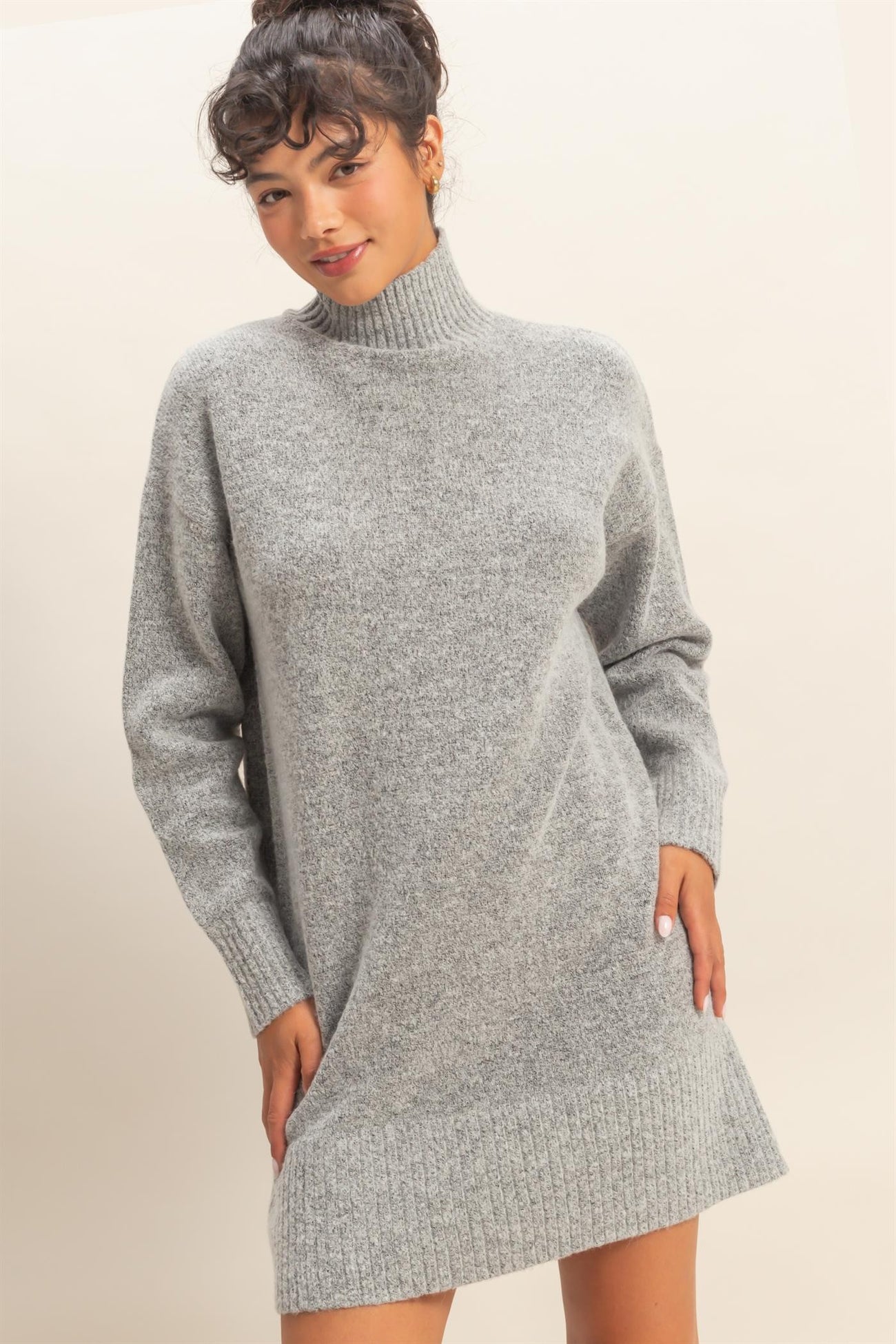 woman wearing a grey turtleneck sweater dress with long sleeves and side pockets