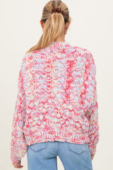 woman wearing a multicolored chunky knit maternity sweater, seen from the back, paired with light blue denim jeans
