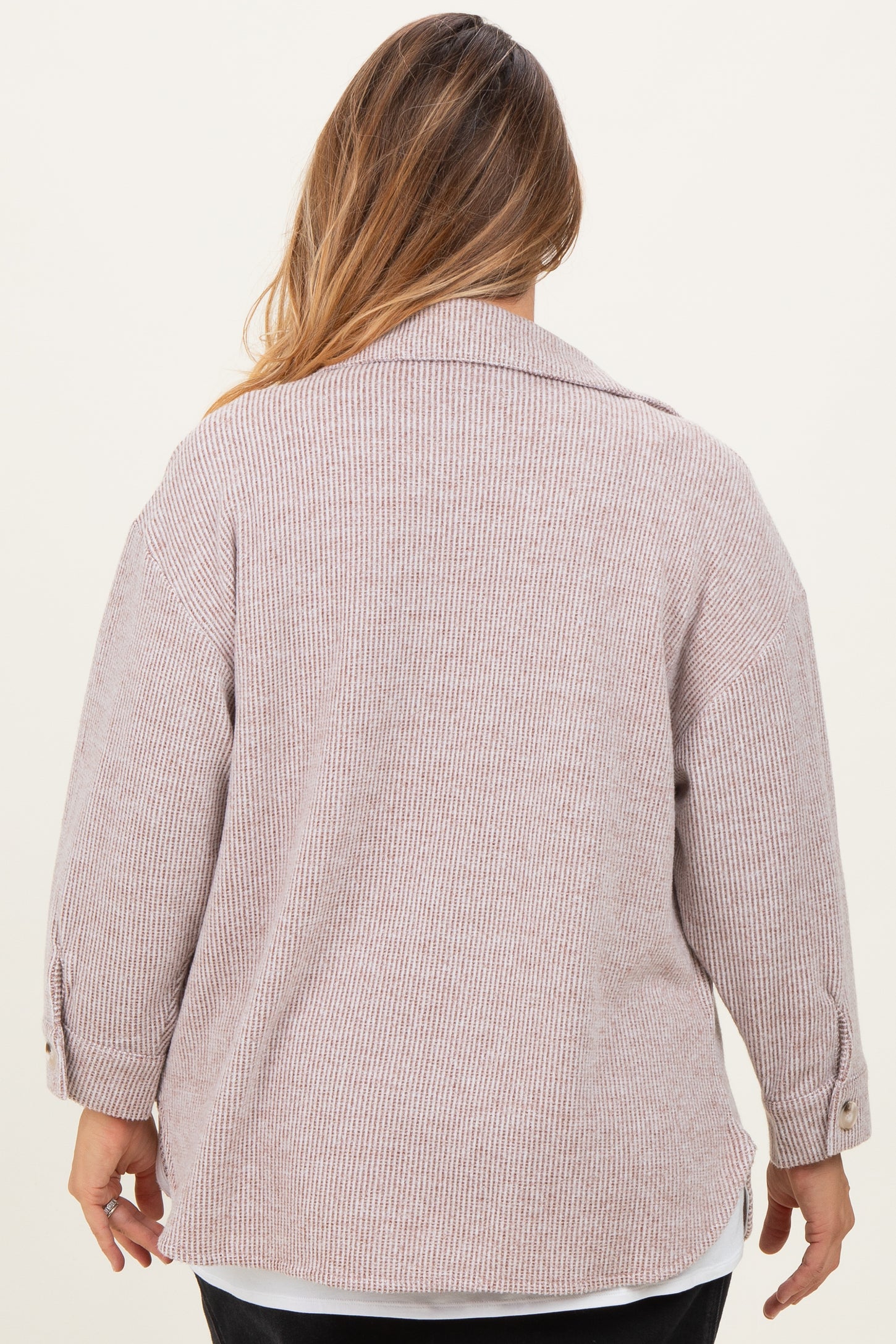 plus size woman wearing a light pink striped maternity sweater with a relaxed fit and buttoned cuffs, viewed from the back