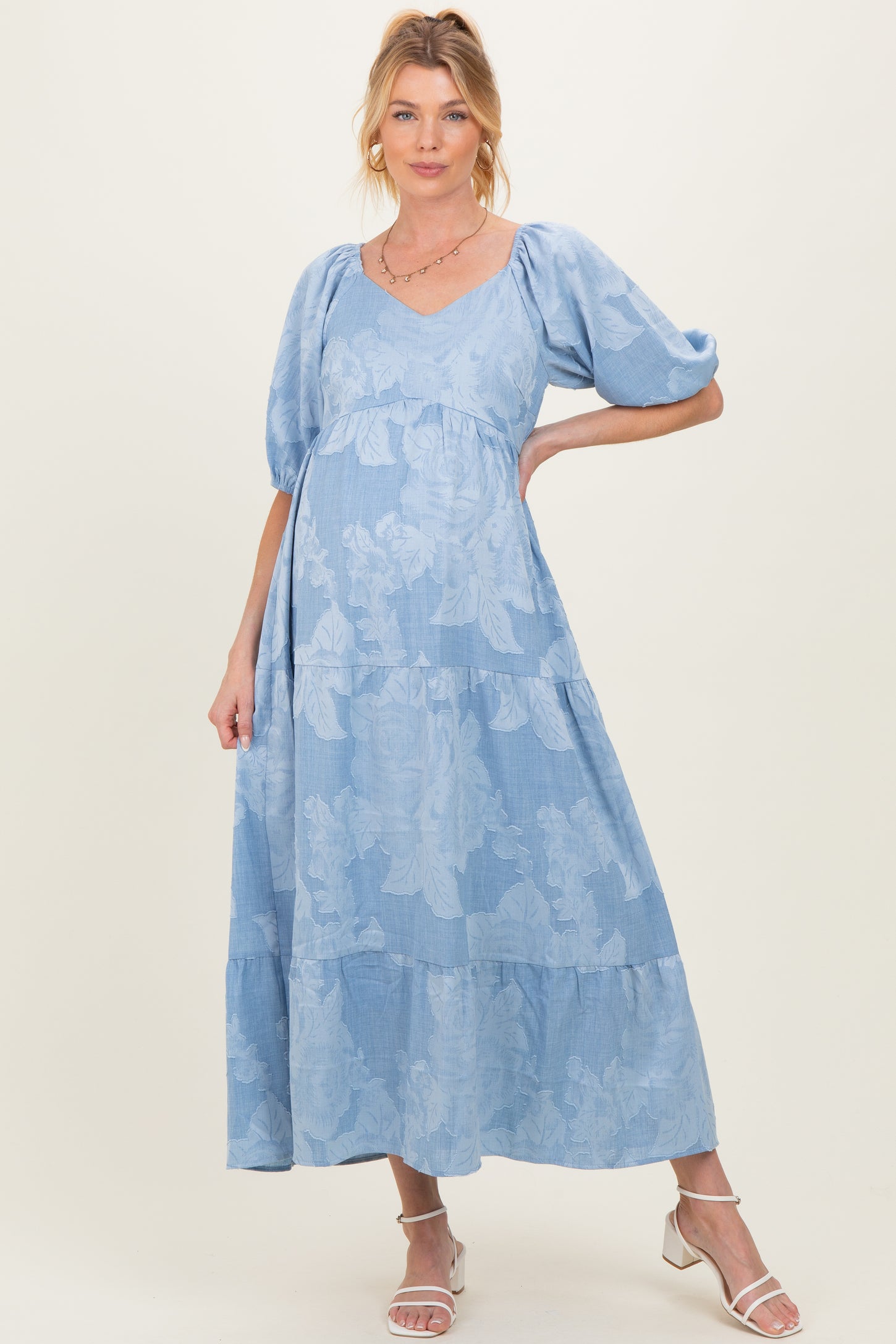 woman wearing a light blue floral maternity maxi dress with puff sleeves and a visible baby bump