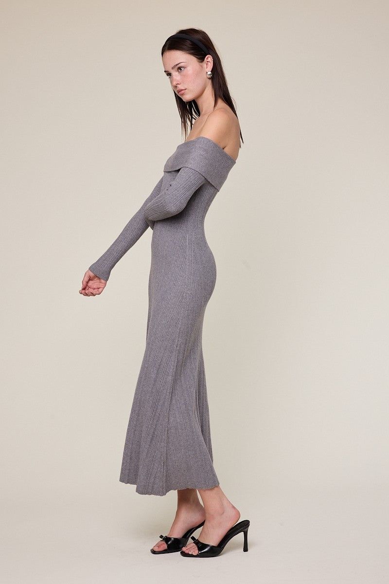 woman wearing a long grey off-the-shoulder ribbed knit dress with long sleeves and high slit, standing sideways