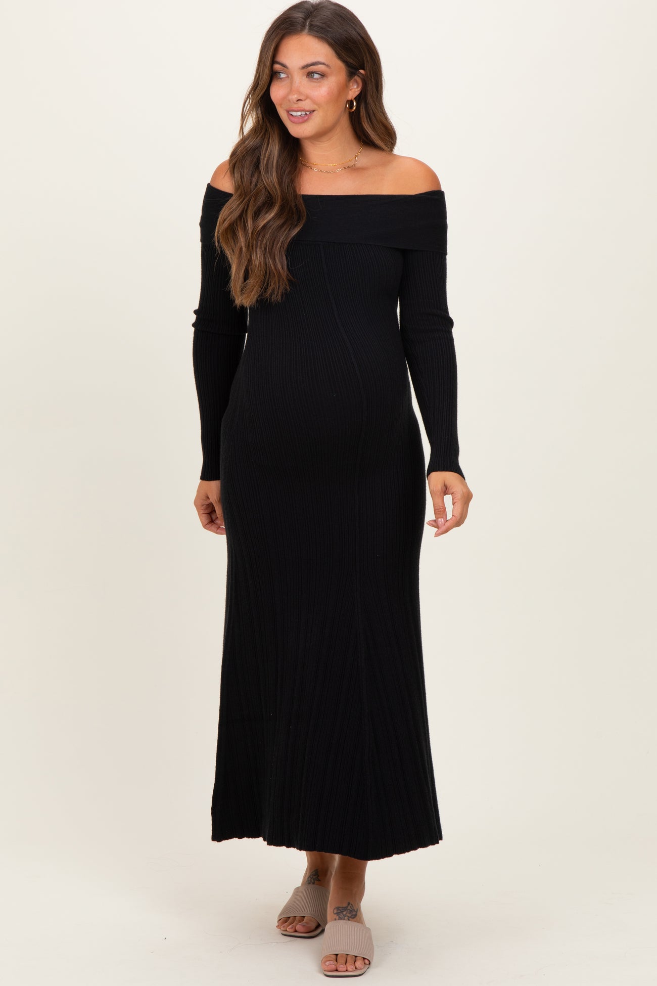 woman wearing a black off-the-shoulder ribbed maternity dress, showing her baby bump