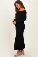 woman wearing a black off-shoulder ribbed maternity dress and holding her baby bump