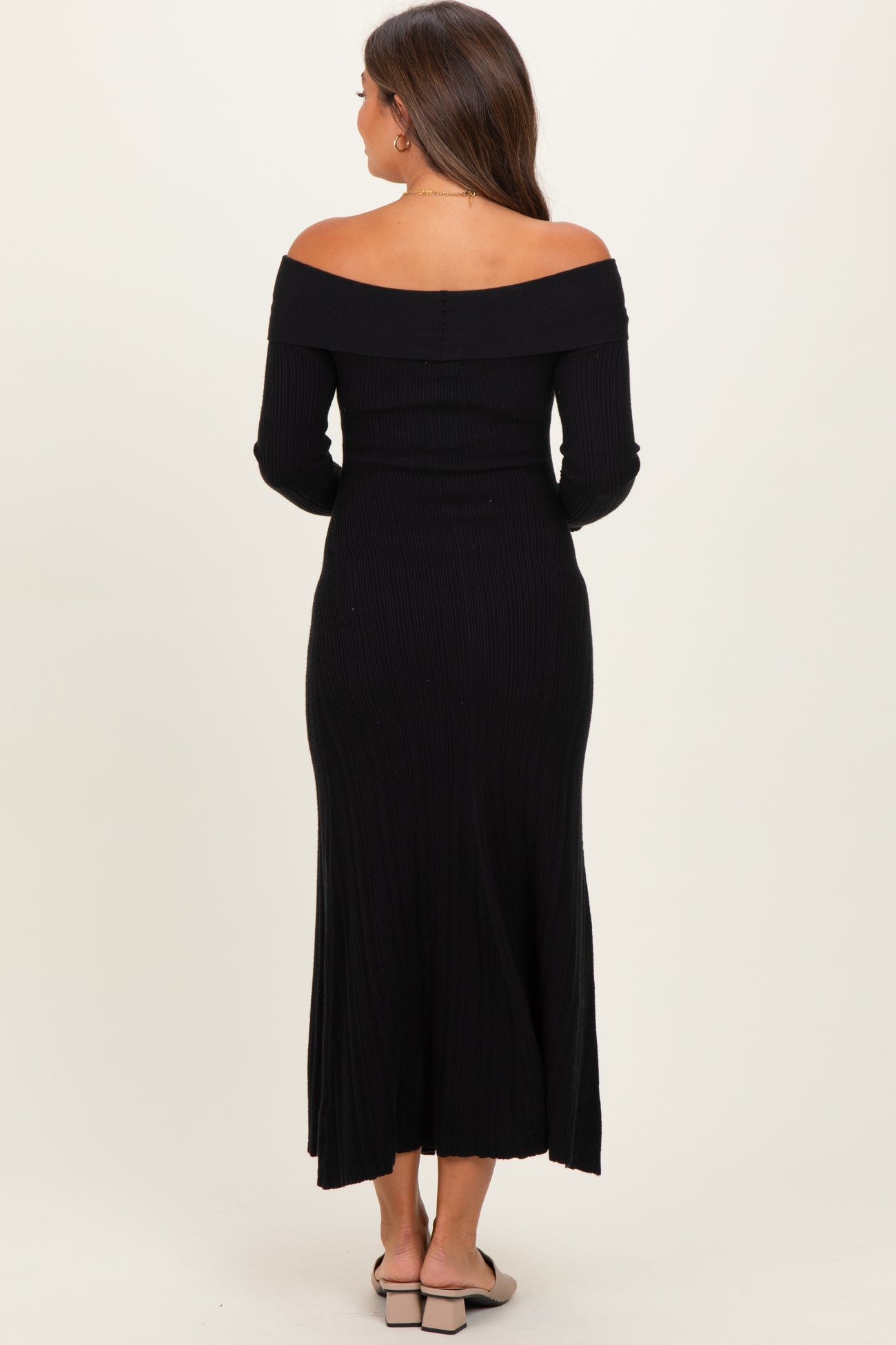 woman wearing a black off-the-shoulder ribbed maternity dress with long sleeves, view from the back