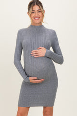 woman wearing a gray ribbed maternity sweater dress and gently holding her baby bump