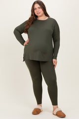 woman wearing a dark green maternity wear long sleeve top and matching leggings, posing with one hand on her hip