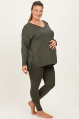 woman wearing a dark green long sleeve maternity top and matching leggings, with a visible baby bump