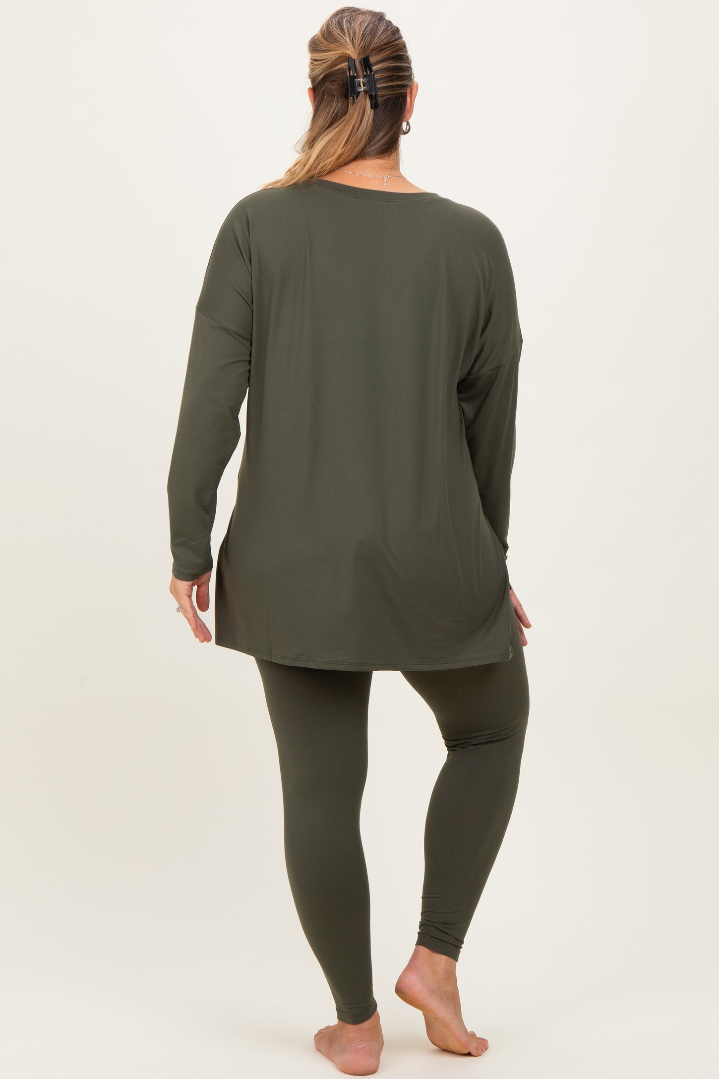 woman wearing a dark green long sleeve maternity top and matching leggings, showing a comfortable fit in maternity plus size