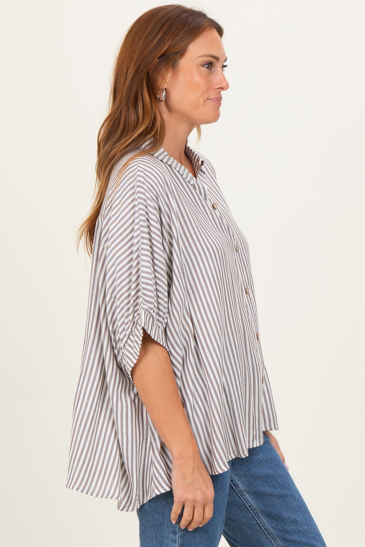 woman wearing a striped button-up oversized blouse with short sleeves and relaxed fit