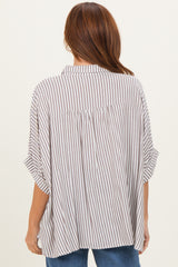 woman wearing a beige and white striped oversized button-up shirt with short sleeves