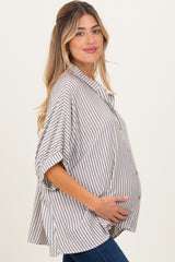 woman wearing a beige and white striped maternity shirt with a button-down front and holding her baby bump