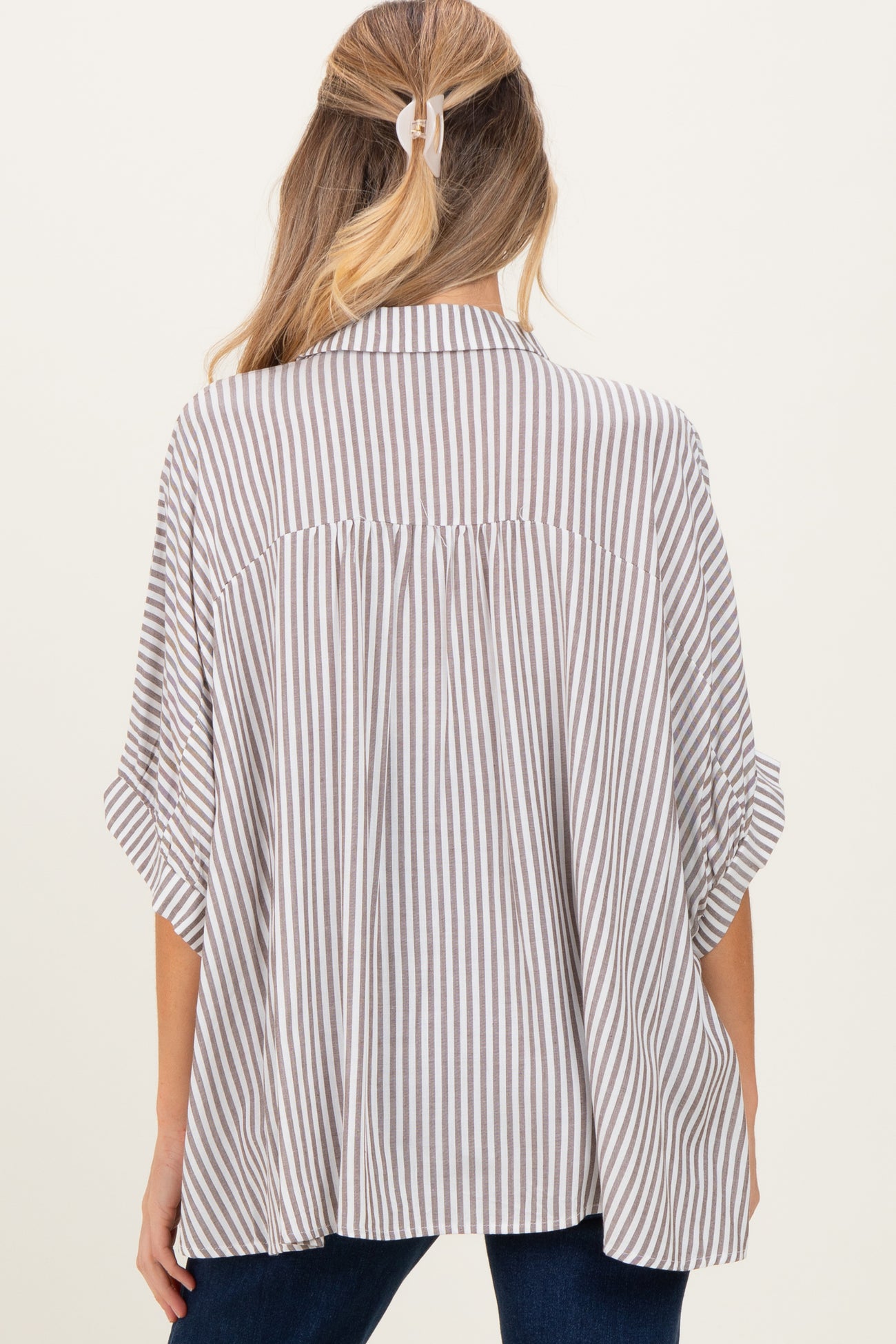 woman wearing a brown and cream striped maternity shirt with a loose fit and rolled sleeves, showing the back view