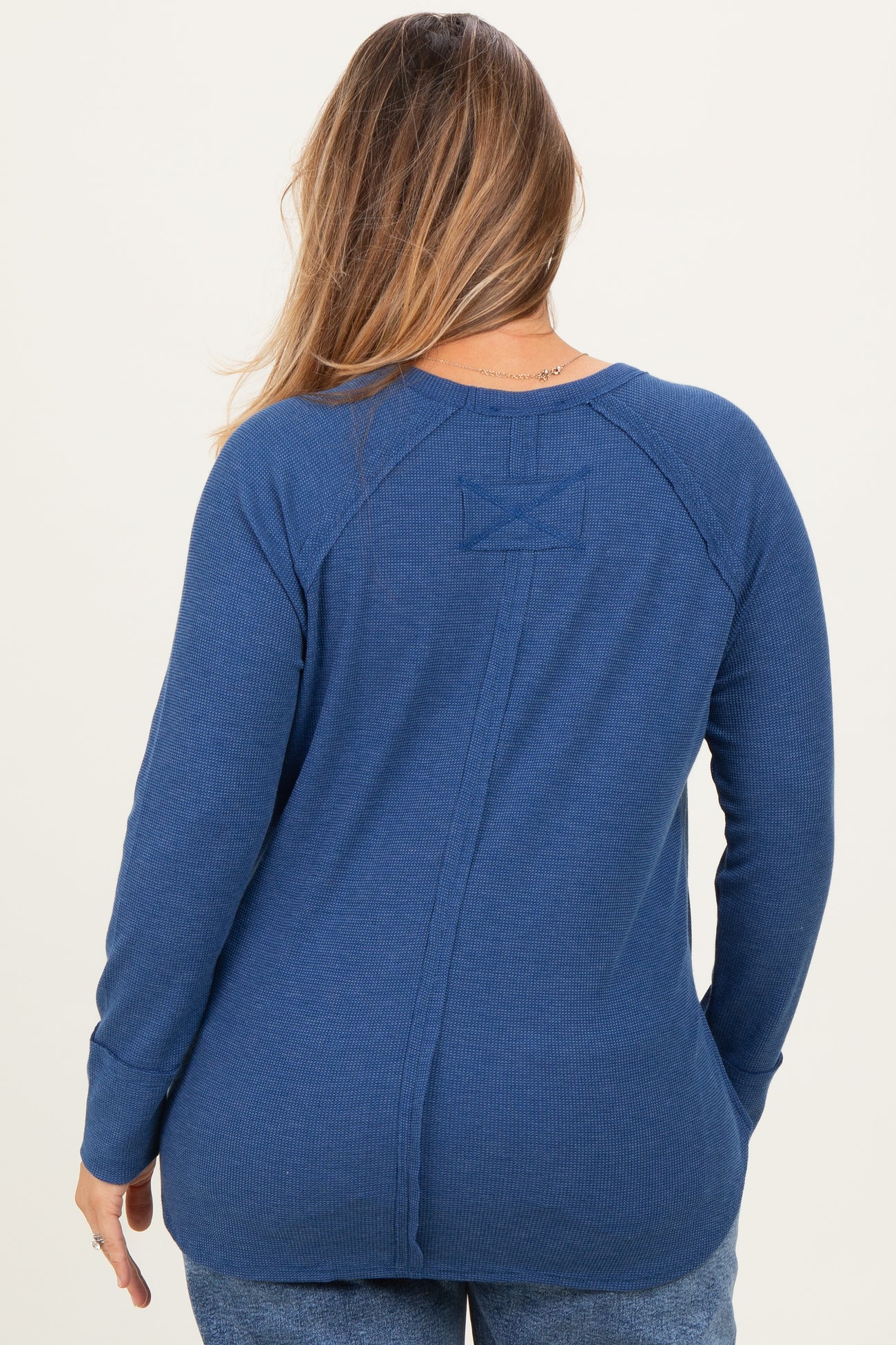 woman wearing a navy blue long sleeve maternity top with a ribbed texture and back seam details