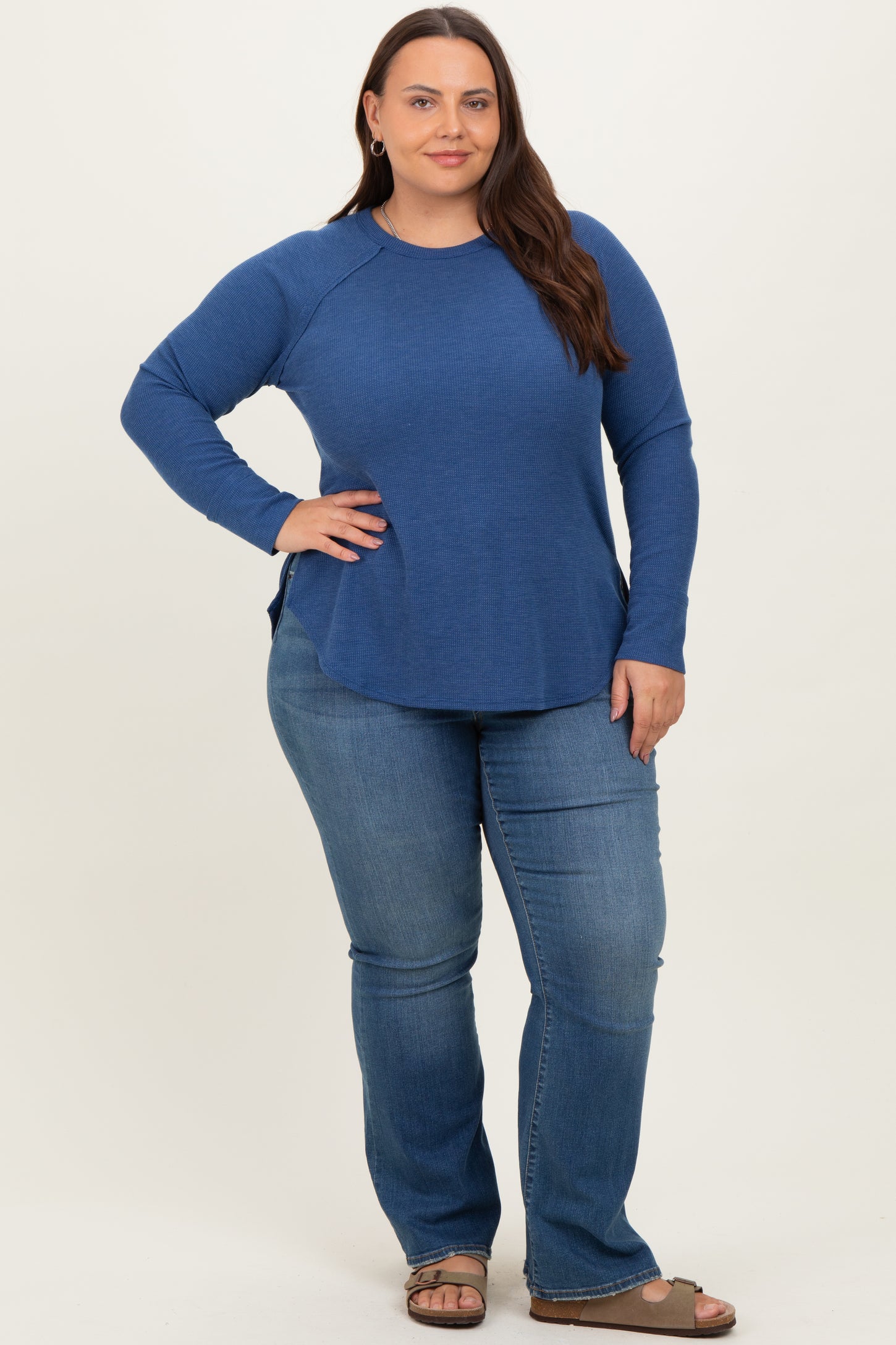 woman wearing a long sleeve blue textured top with side slits and paired with light blue flared jeans