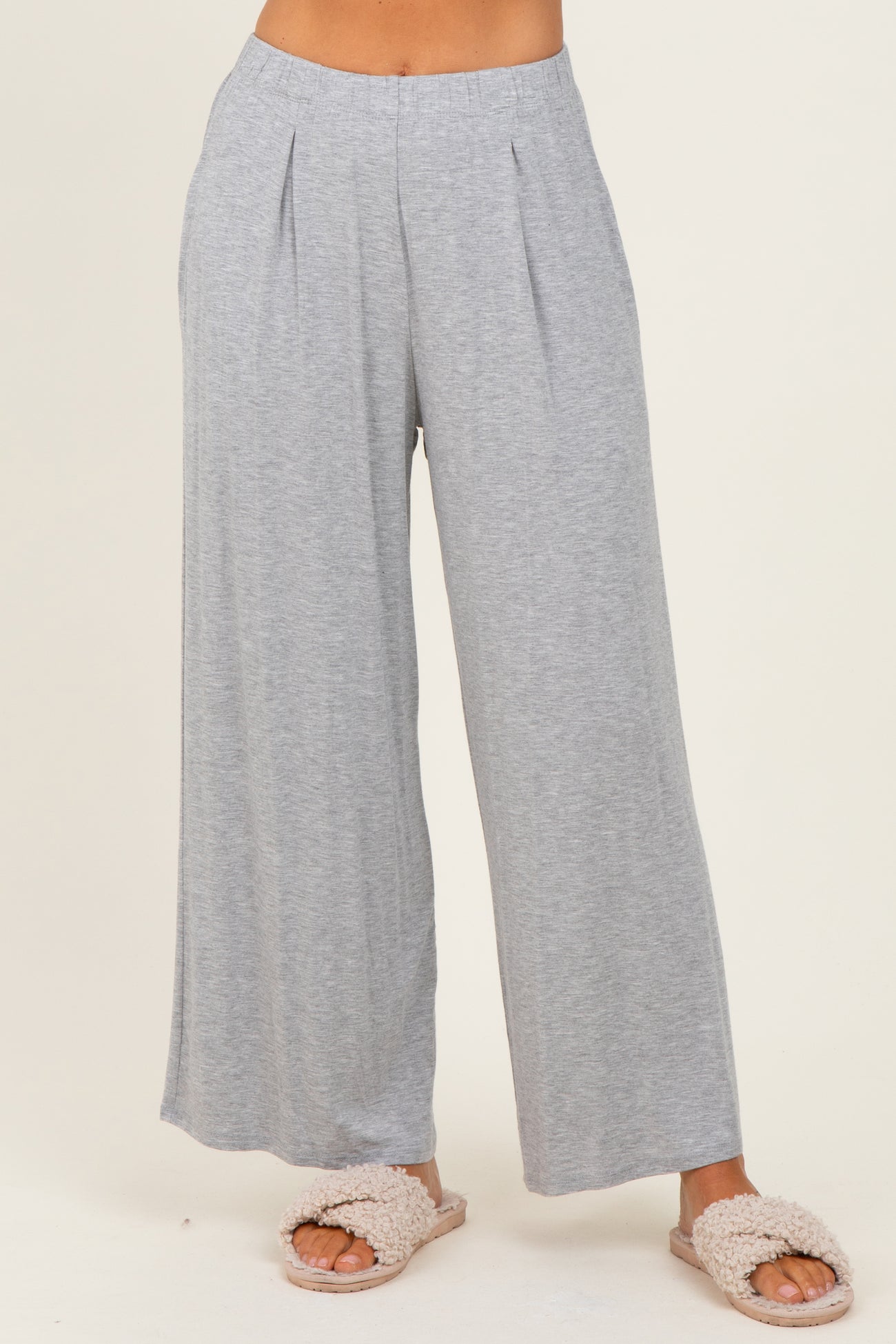 woman wearing light gray wide-leg lounge pants with pleats, styled casually with fluffy slippers
