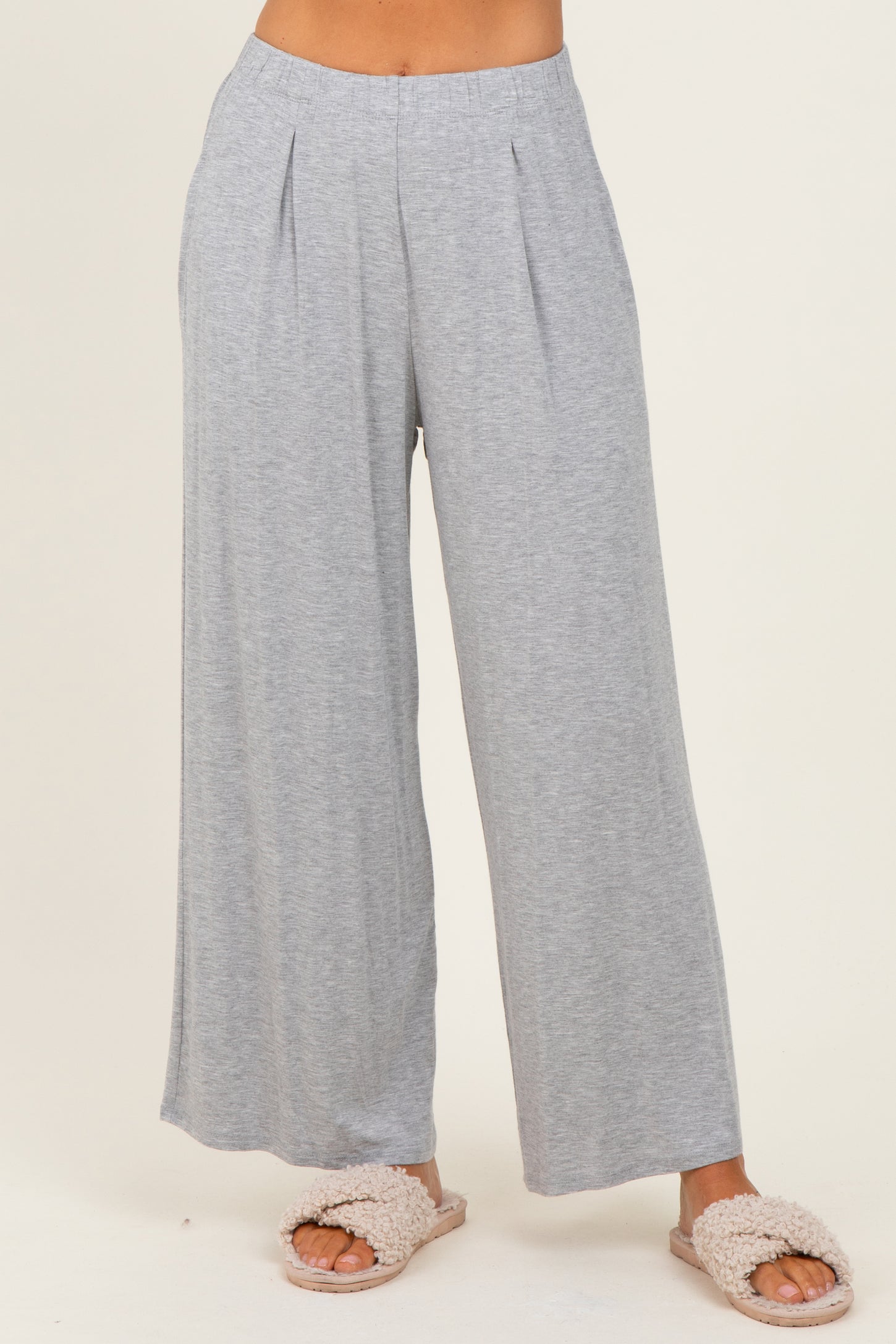 woman wearing light gray wide-leg lounge pants with pleats, styled casually with fluffy slippers