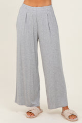 woman wearing light gray wide-leg lounge pants with pleats, styled casually with fluffy slippers