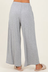 woman wearing light gray wide-leg lounge pants, standing with back to the camera, paired with cozy slippers