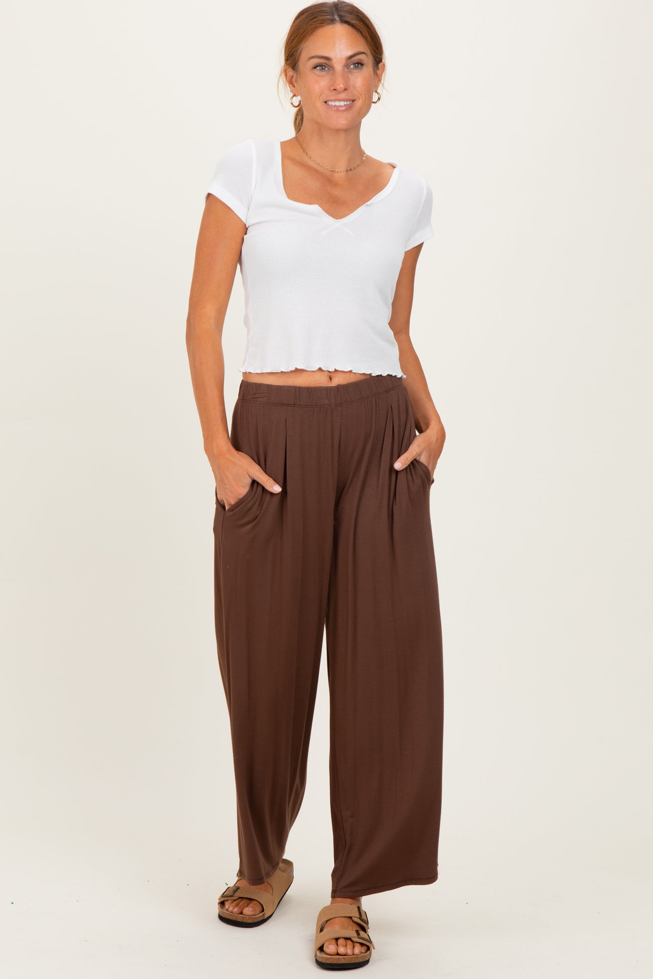 woman wearing a white short sleeve crop top and brown wide-leg pants with pockets