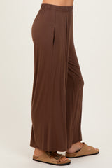 woman wearing brown wide-leg pants with a comfortable elastic waistband, styled casually with slide footwear
