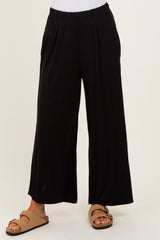woman wearing black wide-leg pants with a pleated front and brown slide sandals