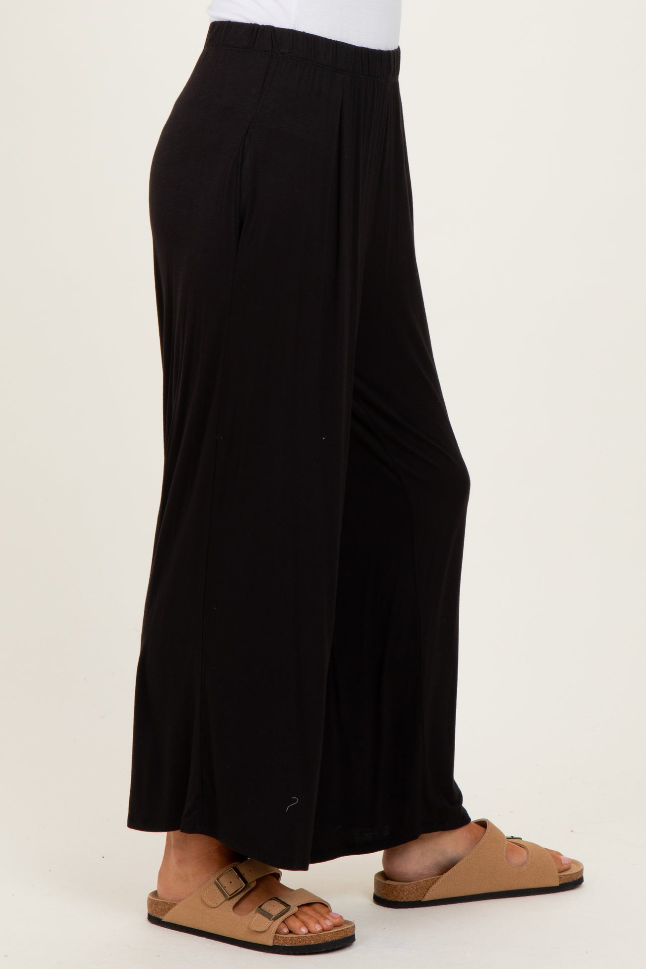 woman wearing black relaxed fit wide leg pants and brown sandals