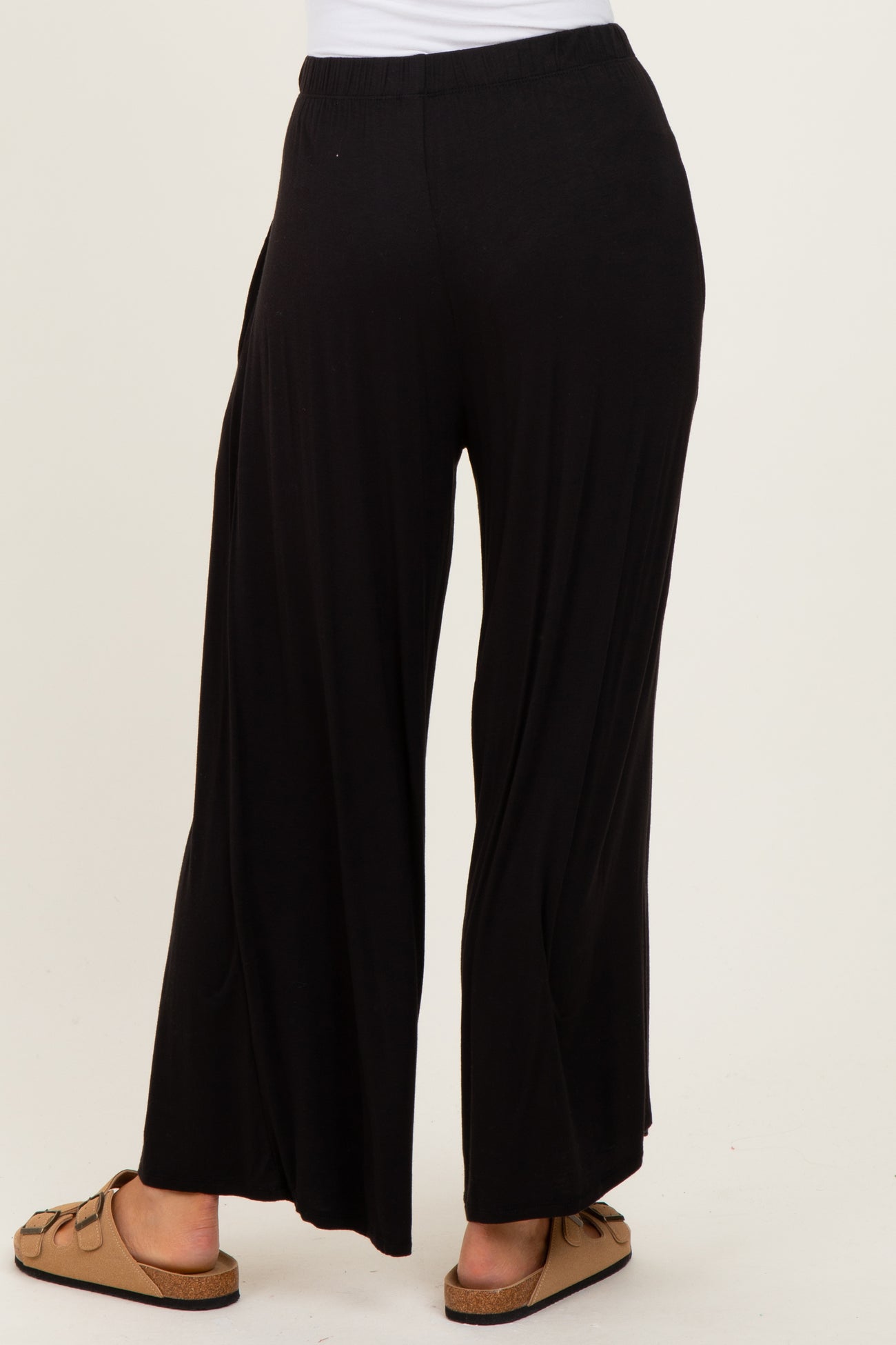 woman wearing black wide-leg pants with a comfortable waistband and paired with light brown sandals