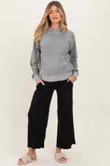 woman wearing a gray maternity hoodie with a front pocket and black maternity pants, styled comfortably with slippers