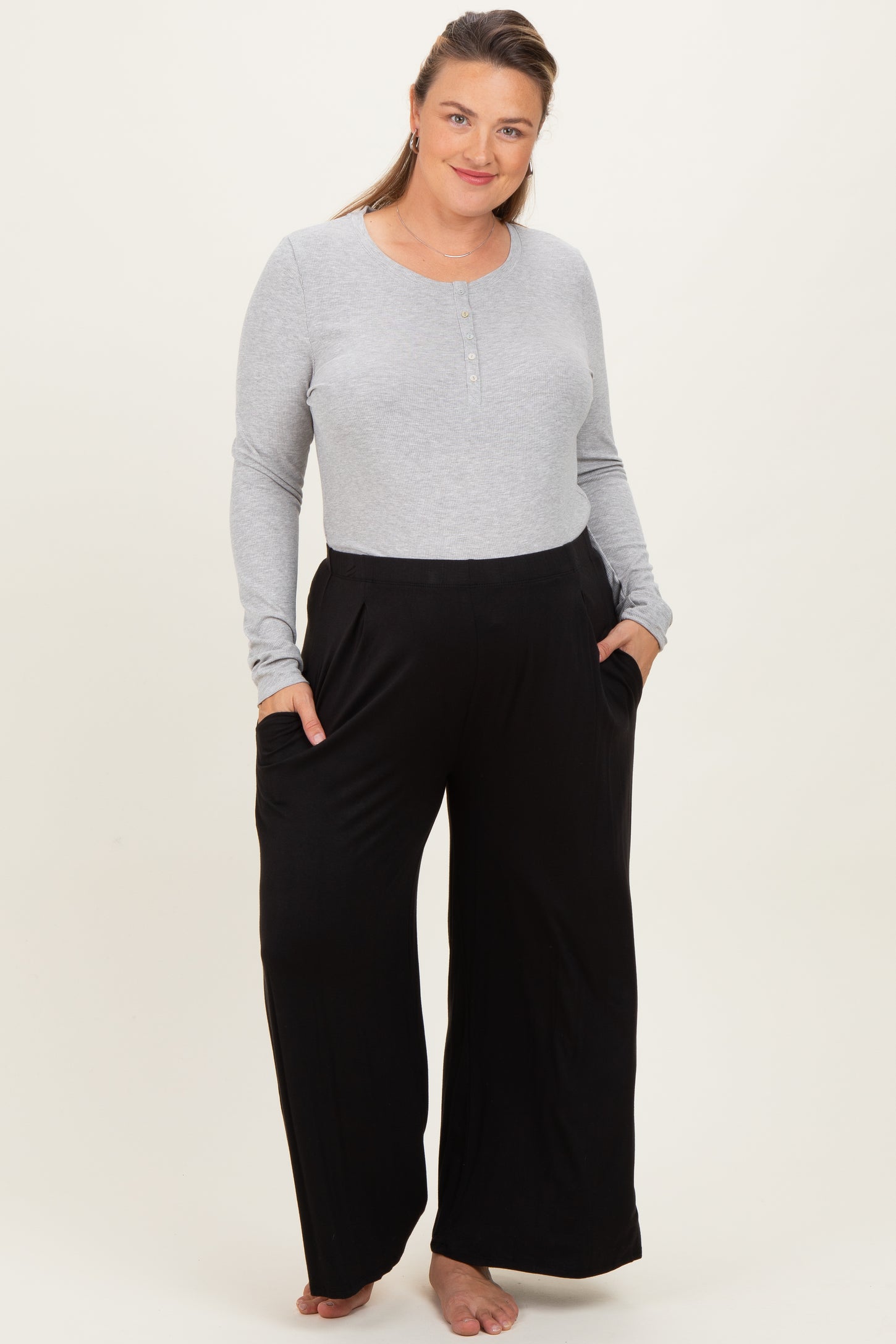 woman wearing a light gray long sleeve maternity top and black wide-leg maternity pants with pockets