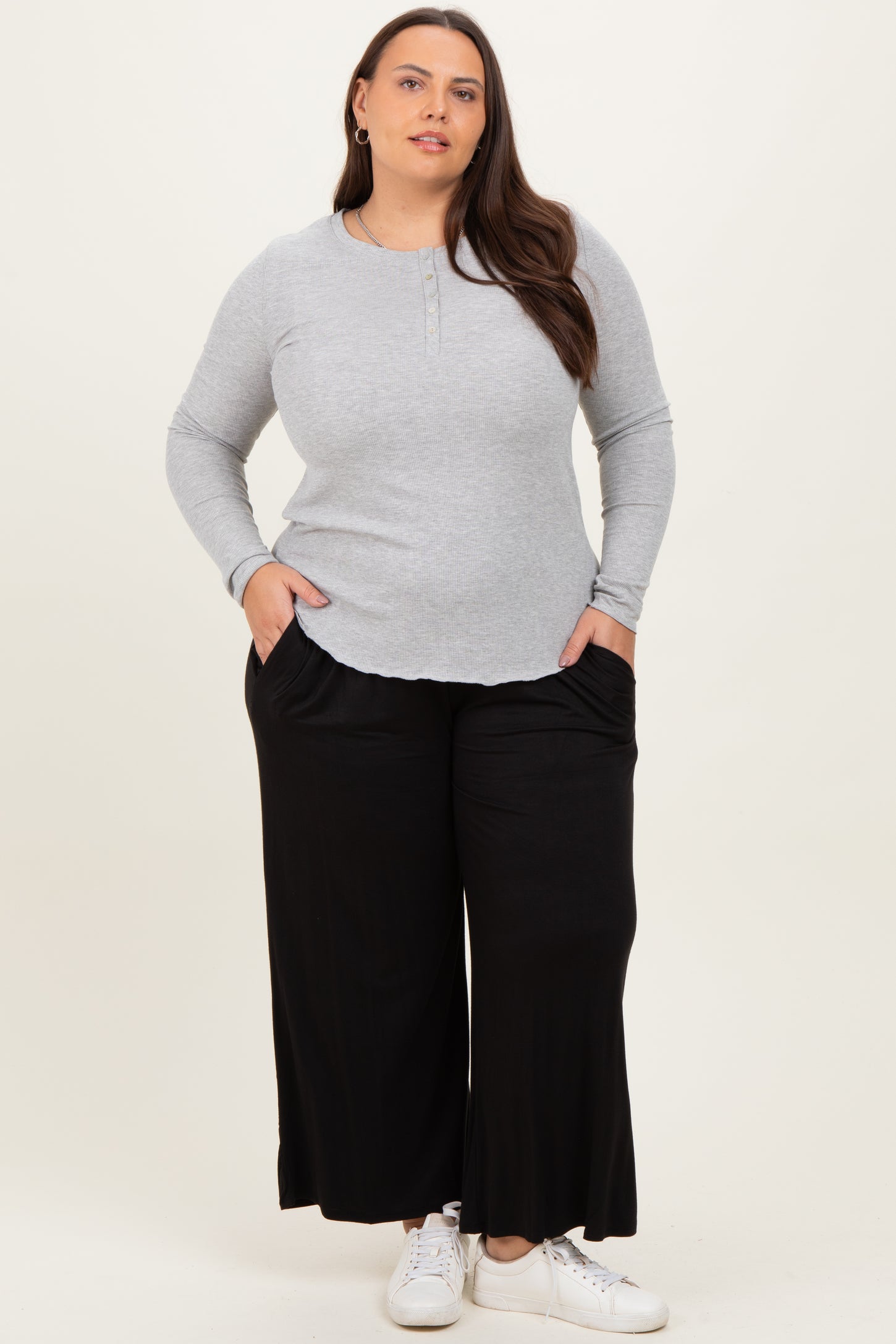 woman wearing a light gray long sleeve henley top and black wide-leg pants with side pockets