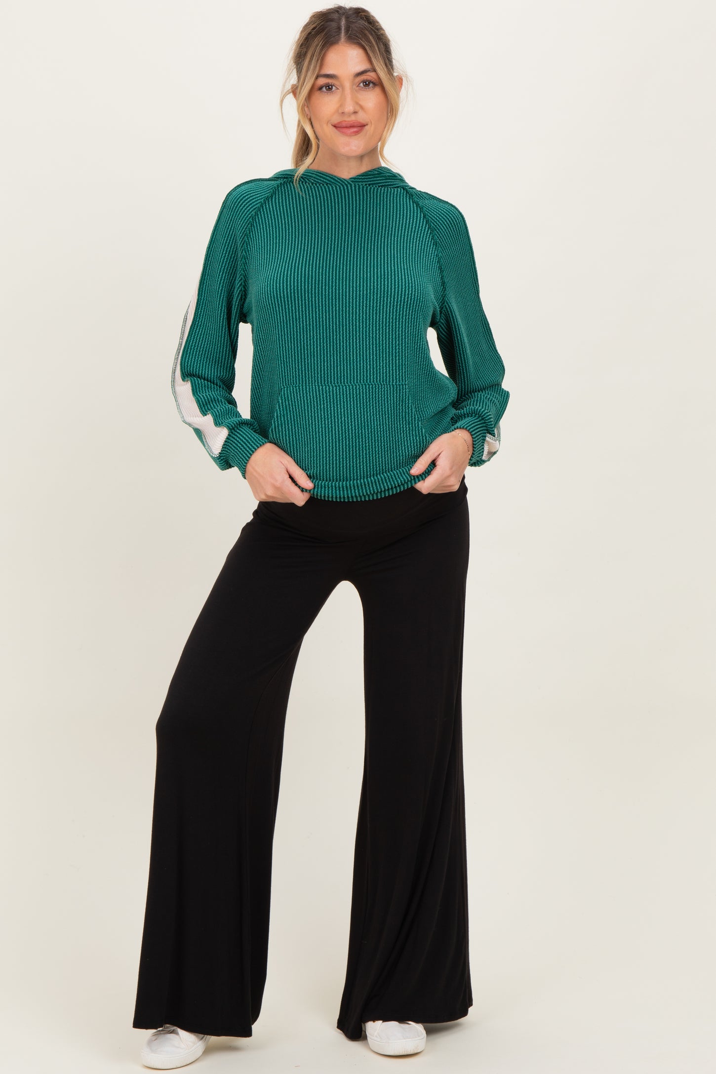 woman wearing a green striped maternity sweater with long sleeves and black wide-leg maternity pants