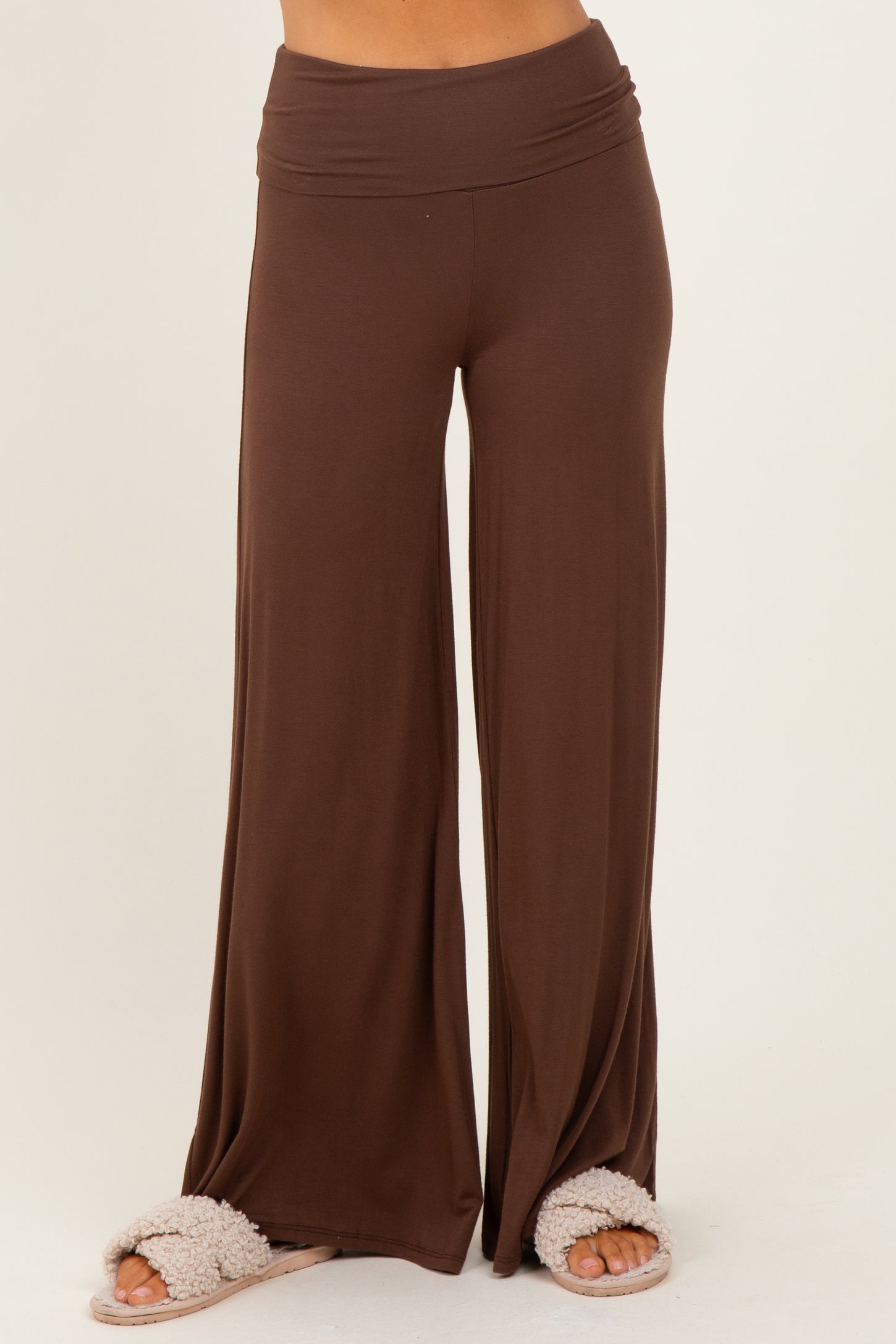 woman wearing brown wide-leg lounge pants with a comfortable waistband and fuzzy slippers