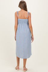 woman wearing a blue and white striped maternity dress with adjustable tie straps and a smocked back