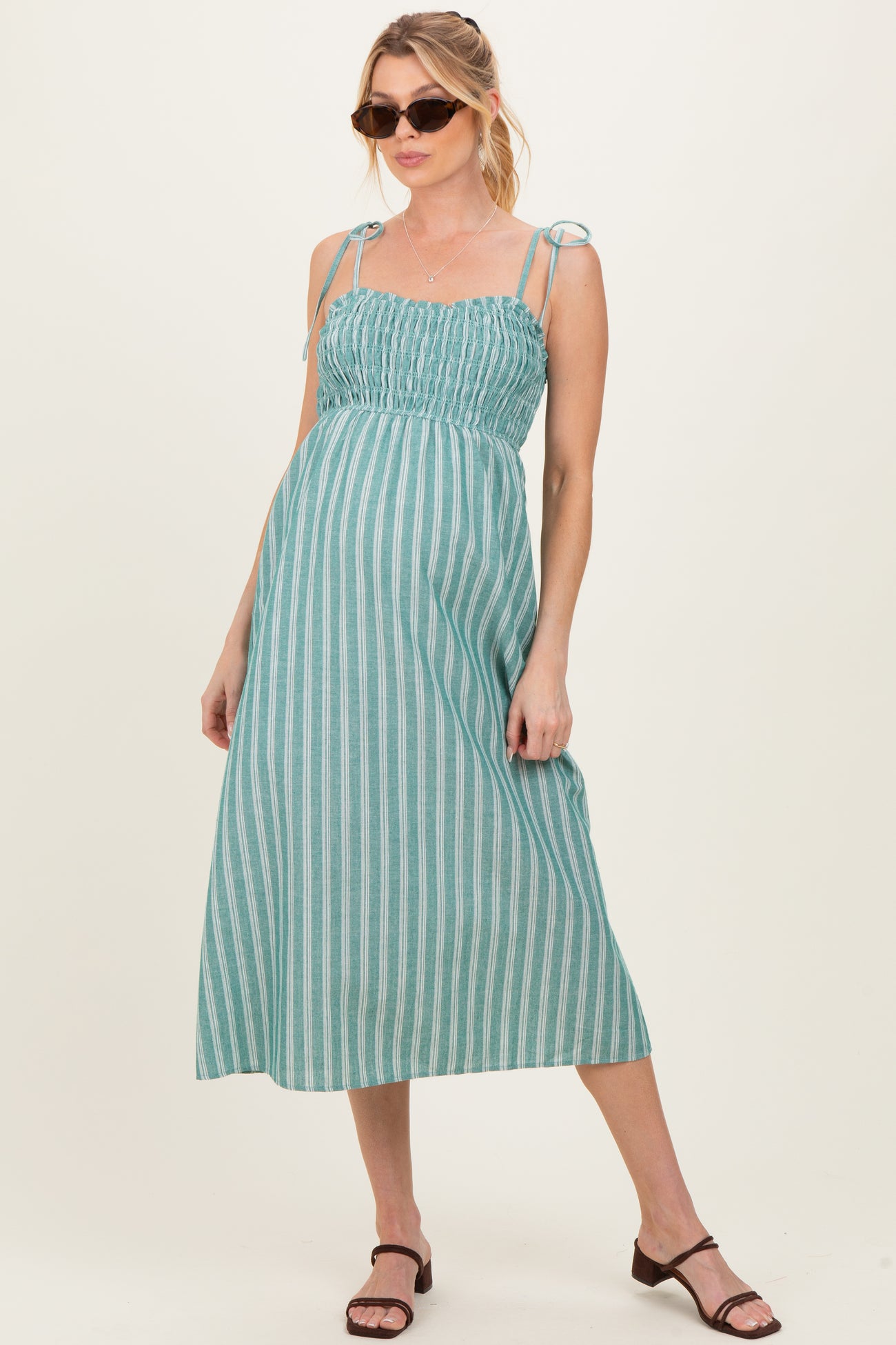 woman wearing a teal striped maternity dress with tie straps and a baby bump visible