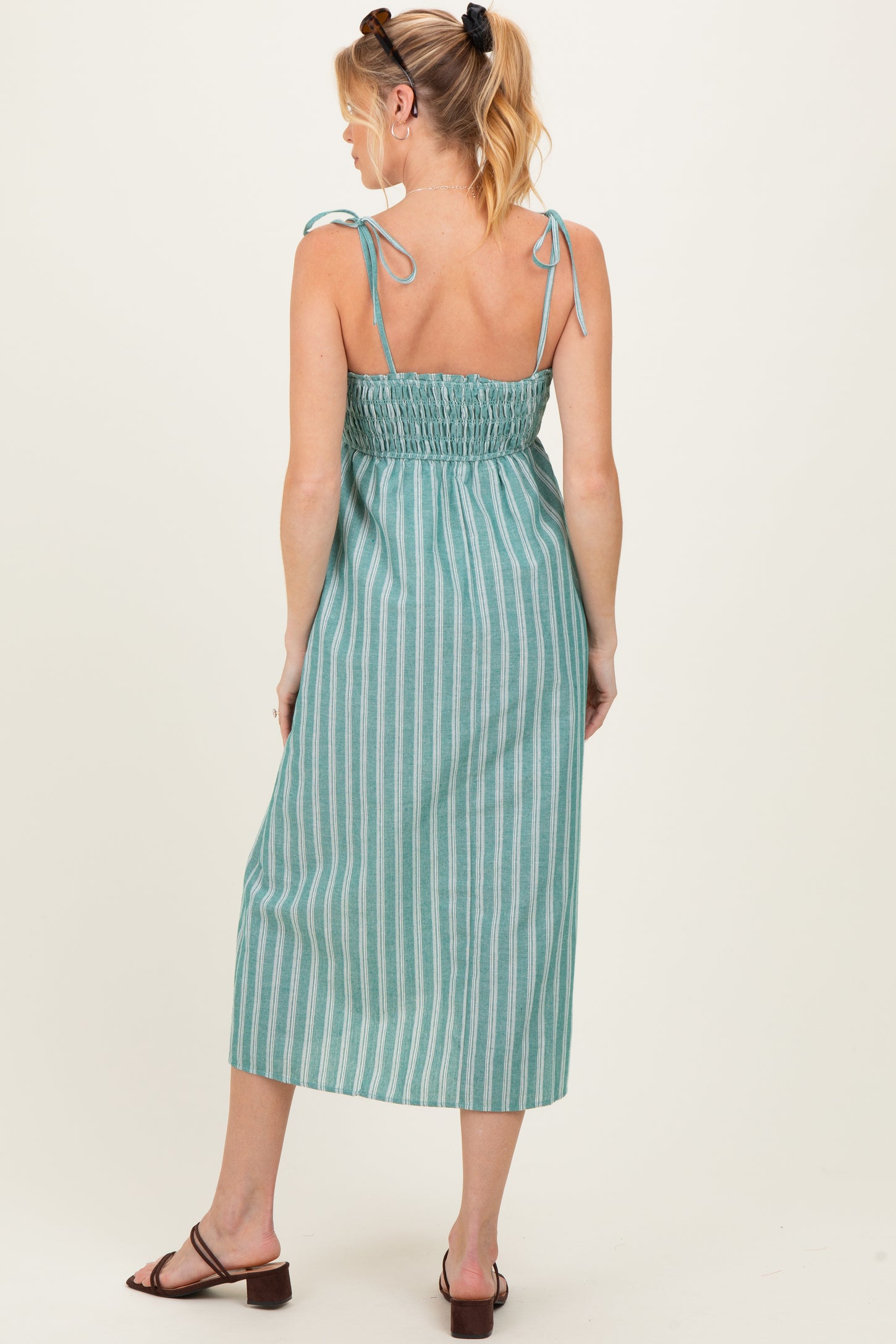 woman wearing a teal and white striped maternity dress with adjustable tie straps and a smocked back