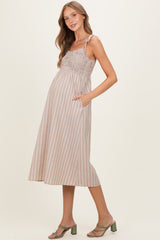 woman wearing a light brown striped maternity dress with smocked bodice and pockets