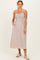 woman wearing a brown and beige striped maxi dress with smocked bodice and tie straps, standing with hands in pockets