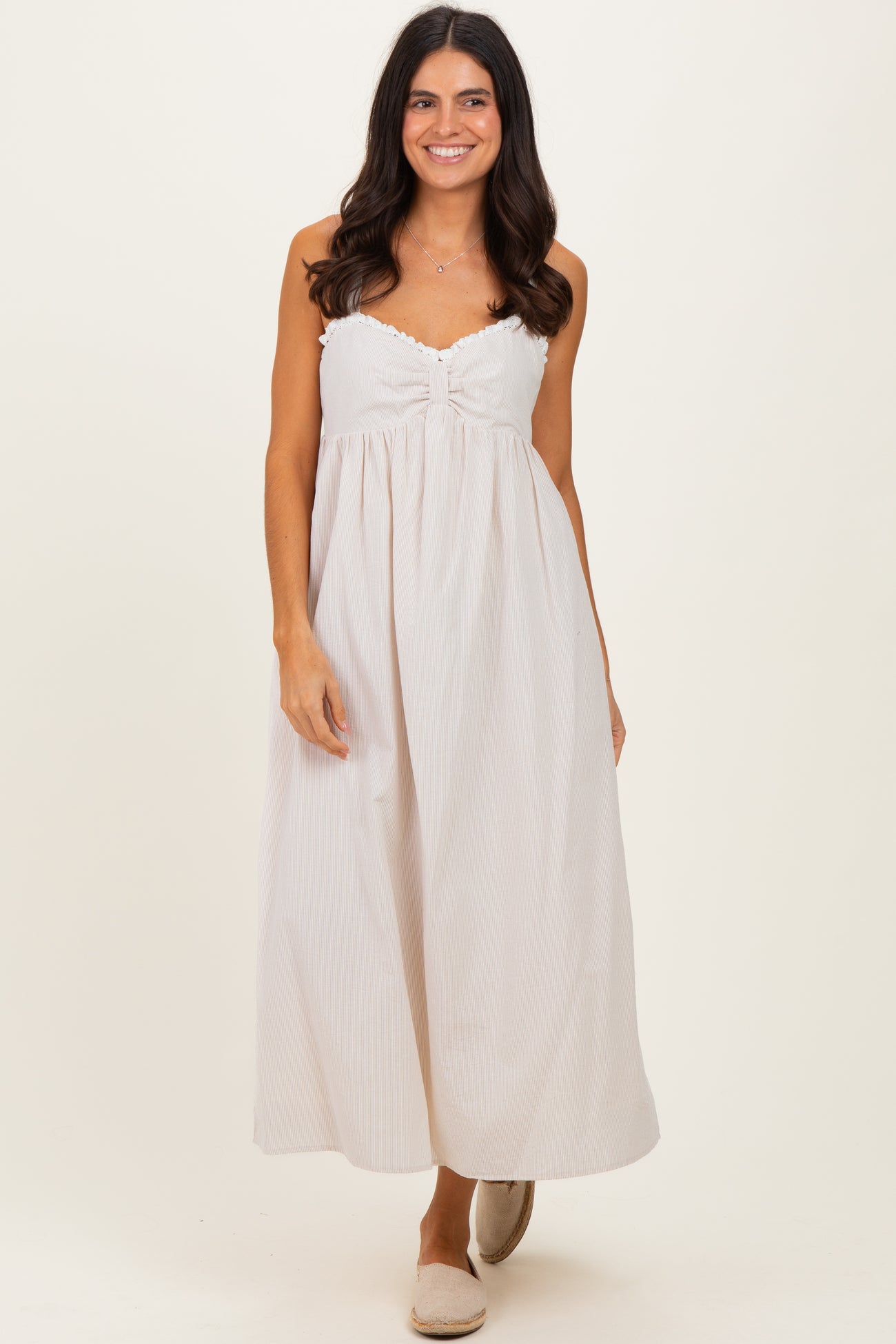 woman wearing a light beige strapless maxi dress with a gathered bodice and a relaxed fit