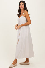 woman wearing a light beige striped maxi dress with adjustable straps and a gathered front detail