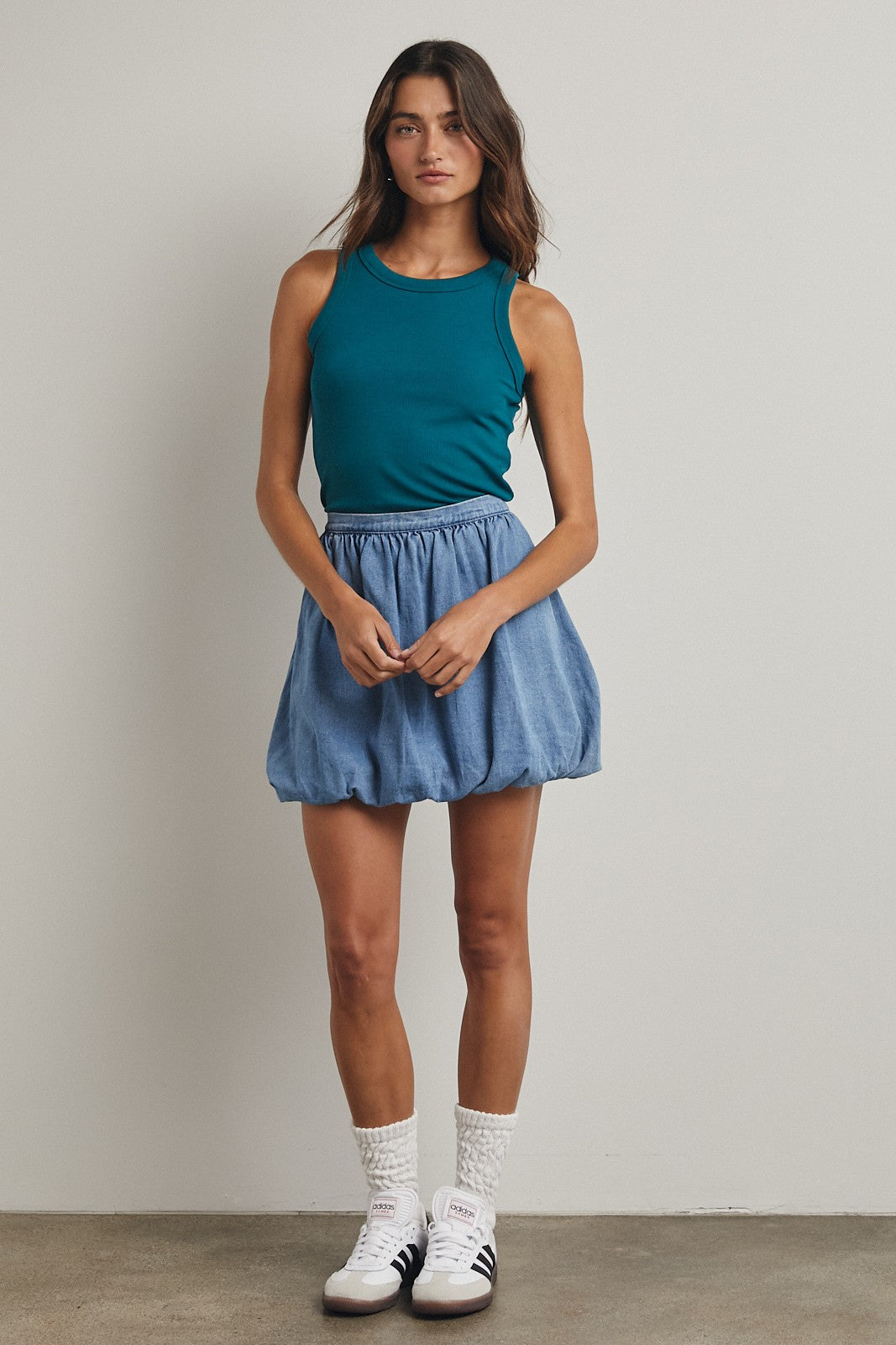 woman wearing a teal sleeveless top and a denim skirt with a balloon silhouette