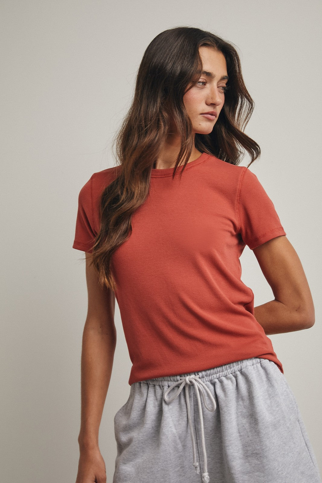 woman wearing a rust colored short sleeve t-shirt and gray sweatpants