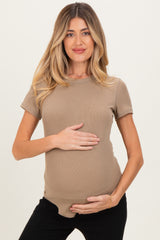 woman wearing a beige ribbed maternity top and holding her baby bump