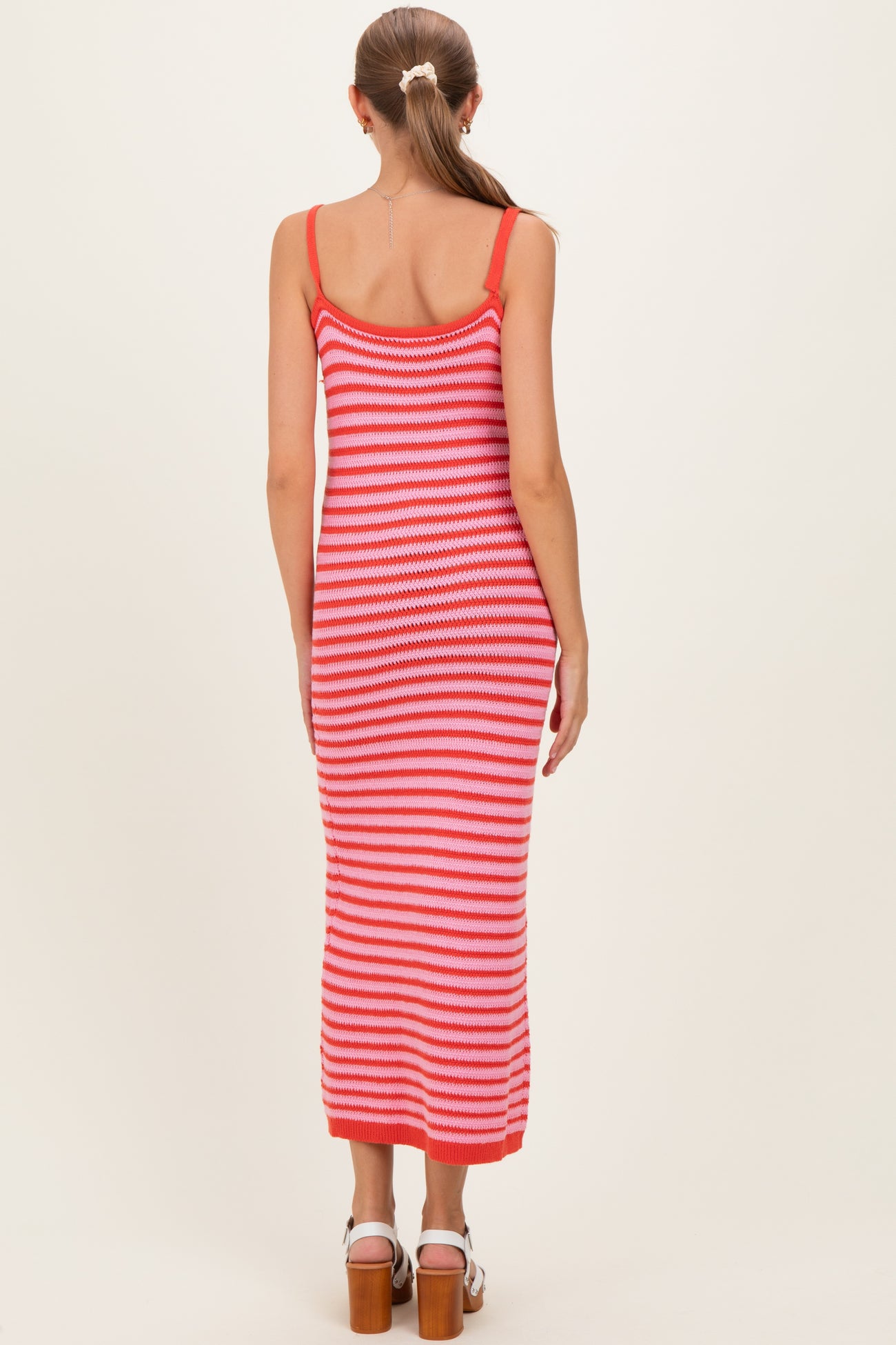 woman wearing a pink and white striped maternity maxi dress with spaghetti straps and a fitted silhouette