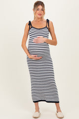 woman wearing a navy and white striped maternity maxi dress with tie straps and holding her baby bump