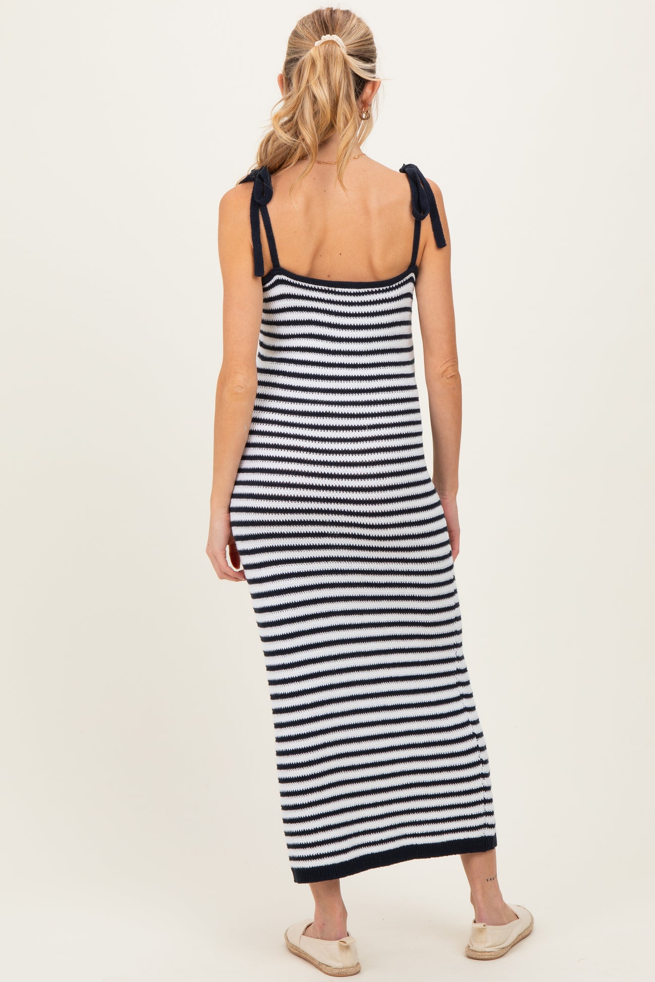 woman wearing a navy and white striped maternity maxi dress with tie straps and a visible baby bump